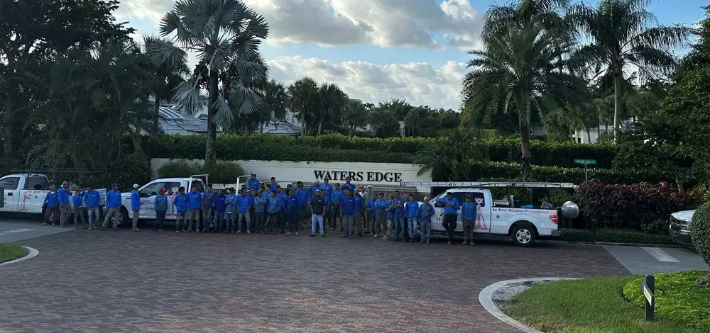 About twenty-five Molsbee Roofing crew members in company shirts, lined up with the company trucks at a job site entrance