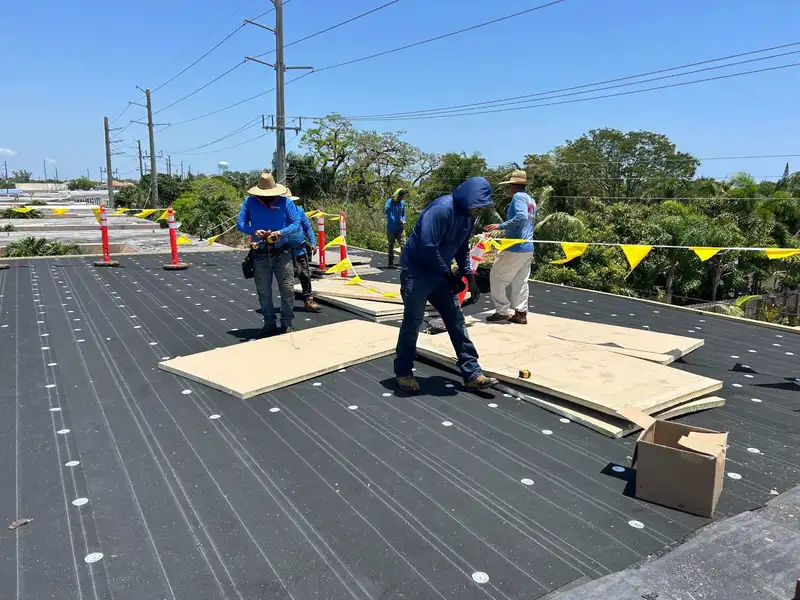 Molsbee crew in company shirts laying board on a flat commercial roof