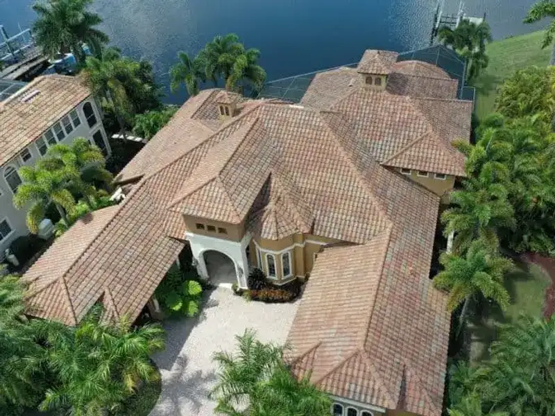 Aerial view of a waterfront estate with a repaired barrel tile roof